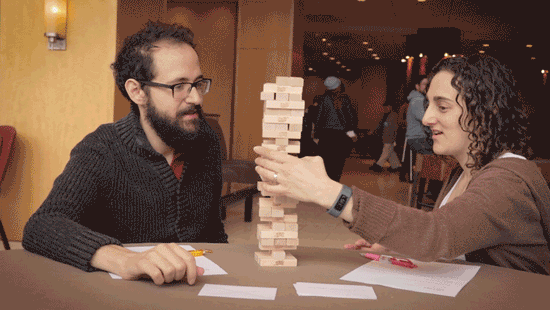 two players looking surprised as a jenga tower falls over