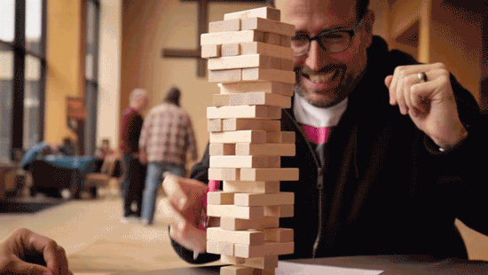 one player looking nervous as he tentatively touches a jenga tower